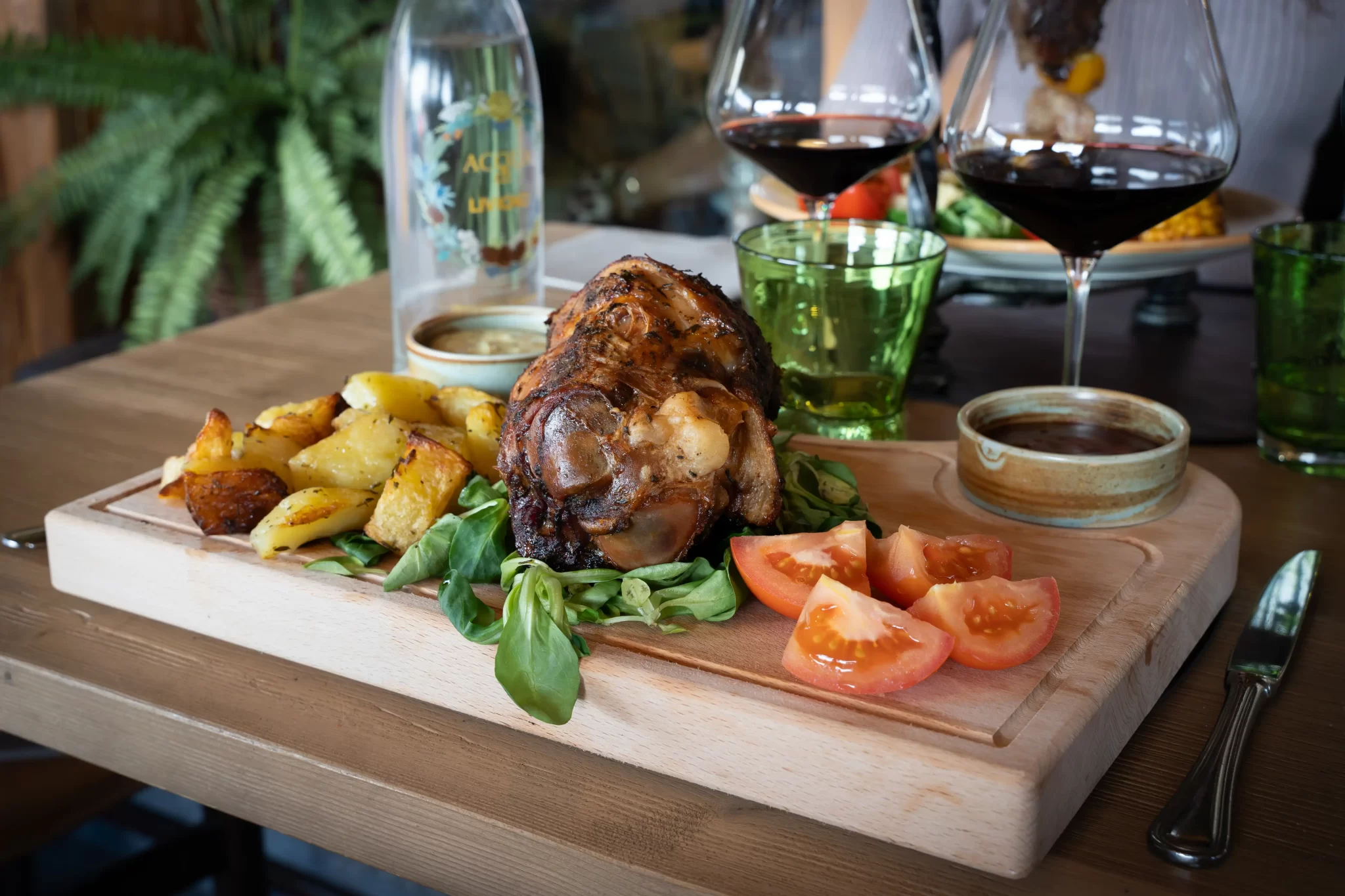 Brasato di carne con patate arrosto e pomodori freschi su un tagliere di legno.