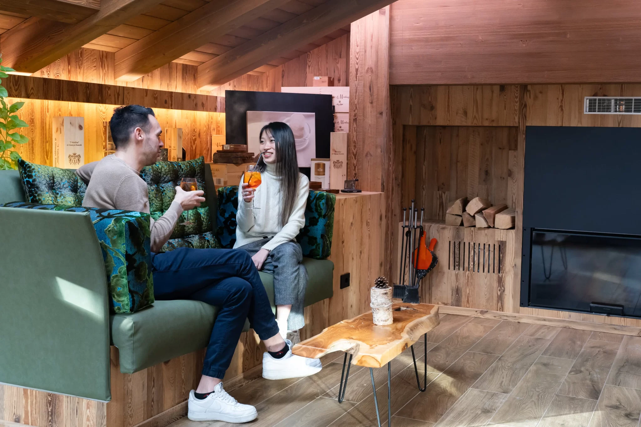 Coppia che beve un drink in un accogliente soggiorno in legno.