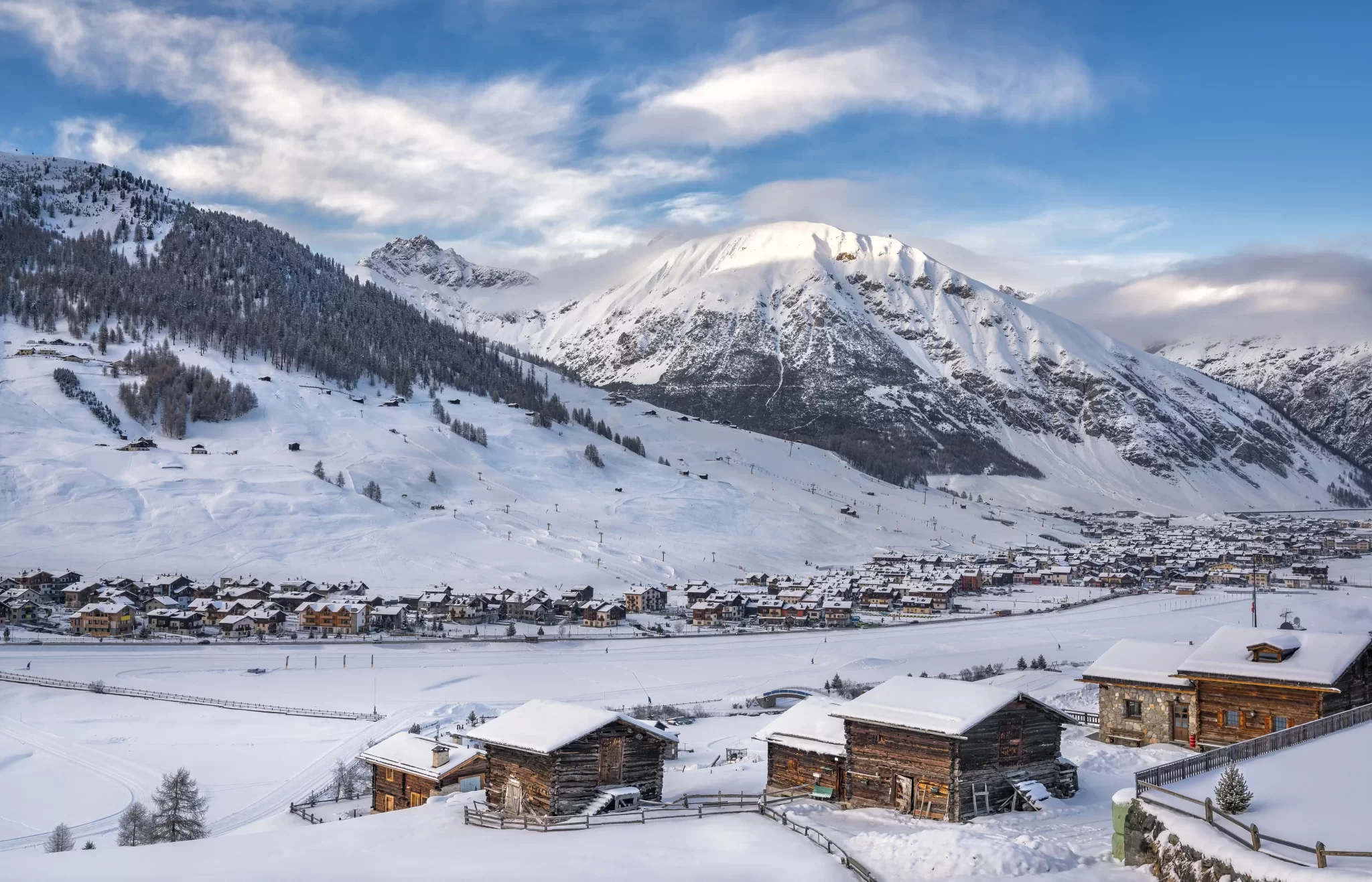 Panorama invernale di Livigno, con montagne innevate, baite e un villaggio alpino.