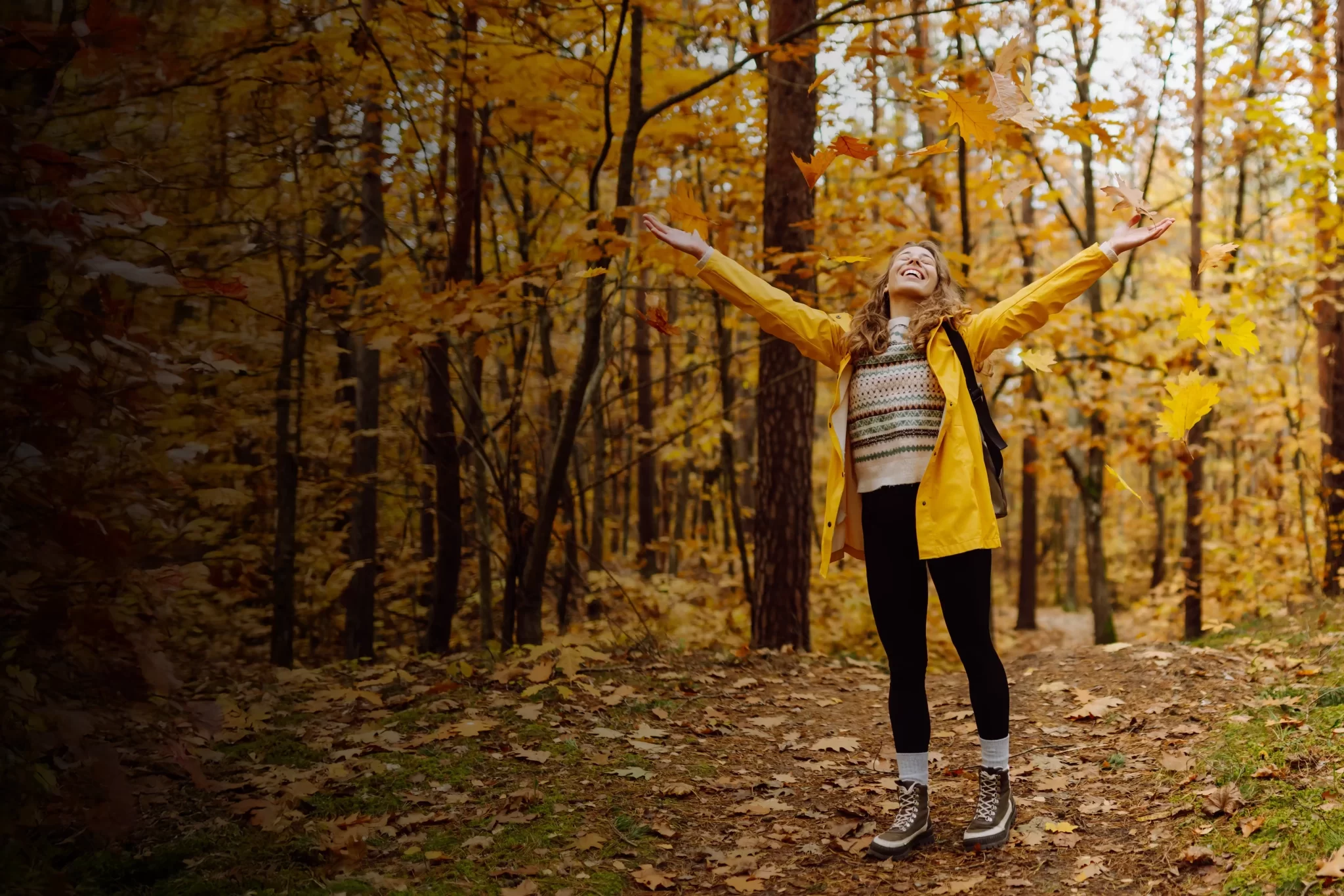 Donna felice in una foresta autunnale con foglie gialle.