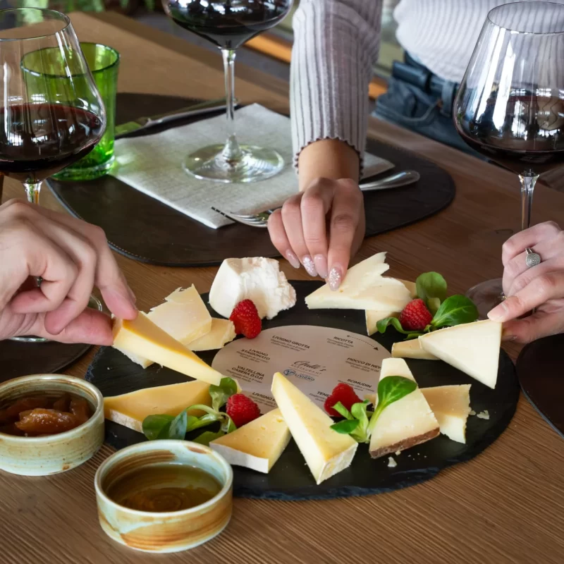 Degustazione di formaggi con vino rosso e contorni a tavola.