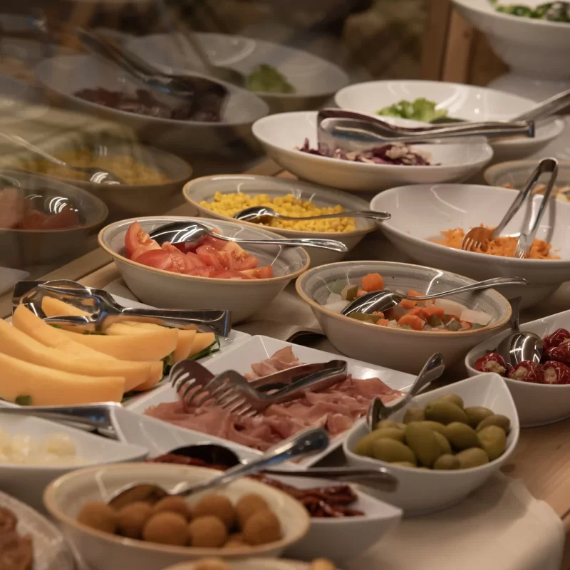 Buffet con una varietà di piatti, tra cui frutta, verdure e antipasti.